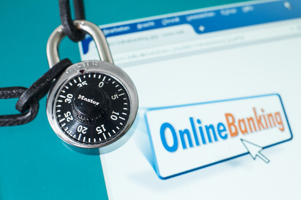 Vorhängeschloss mit Zahlenkombination liegt auf einem Bildschirm mit der Aufschrift Online-Banking