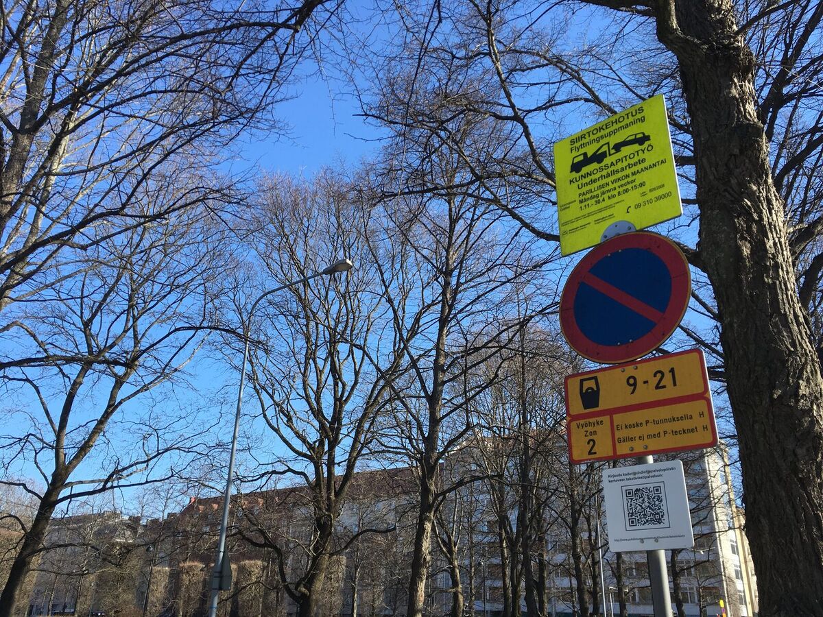 Verkehrsschilder an einem Baum, darunter ein Schild mit QR-Code